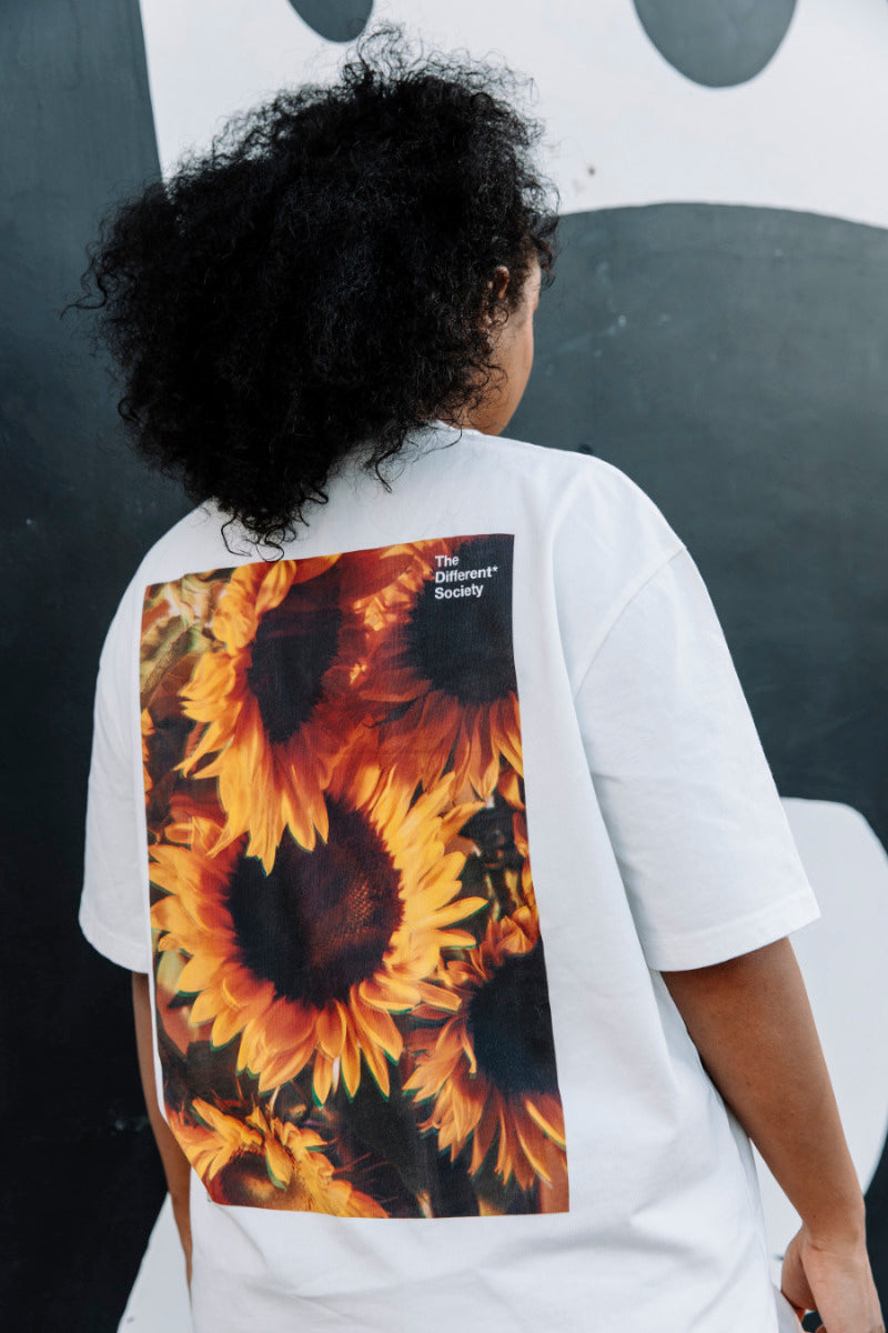 Person wearing a white t-shirt with a yellow sunflower design ob the back.