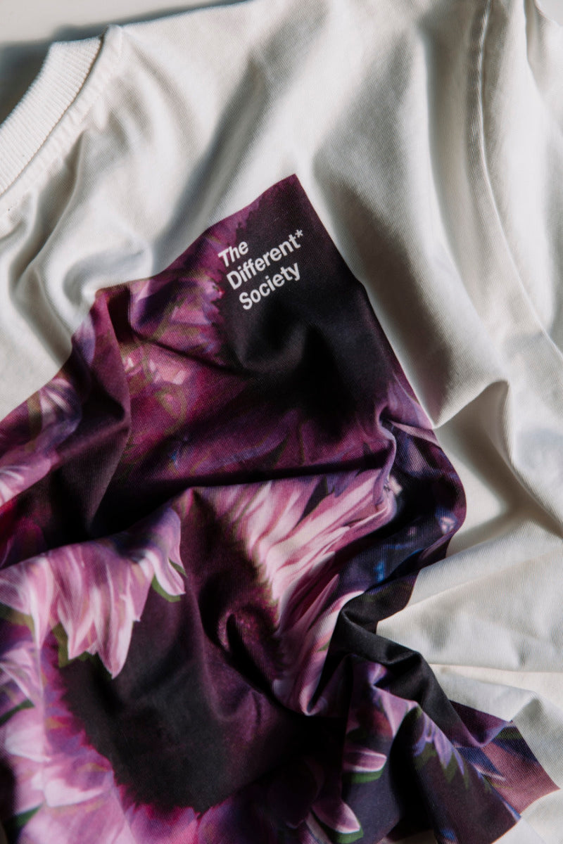 Close up of the back of the purple sunflower t-shirt. The t-shirt is white, with a print featuring purple sunflowers